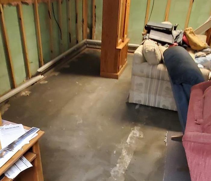 The concrete floor is exposed after removal of the water and walls are exposed after removing wet and damaged paneling