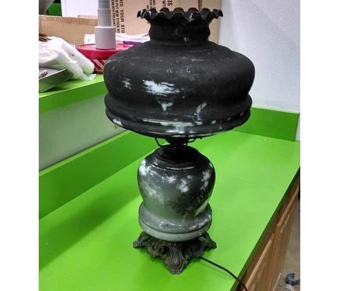 The lamp has survived a recent house fire but is covered in soot and is black in color
