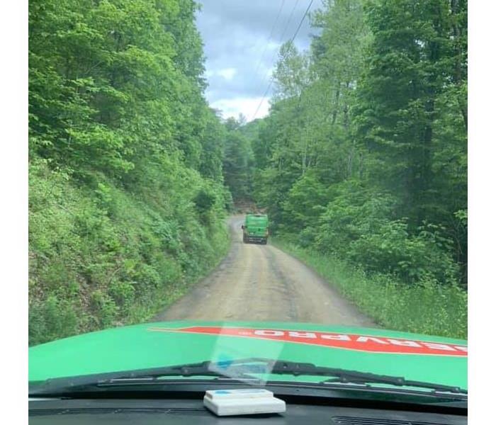 Van traveling down a winding dirt road with both sides lined with trees
